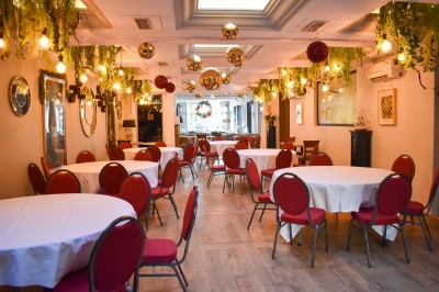 Équipe de restaurant posant en groupe devant un mur décoratif, avec deux enfants tenus par des adultes au centre.