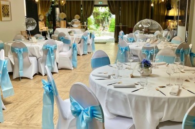 Équipe de restaurant posant en groupe devant un mur décoratif, avec deux enfants tenus par des adultes au centre.