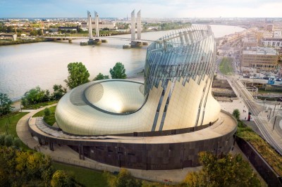 Flacons et éléments décoratifs sous cloches en verre sur une table éclairée dans un espace moderne et tamisé.