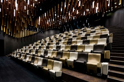 Flacons et éléments décoratifs sous cloches en verre sur une table éclairée dans un espace moderne et tamisé.