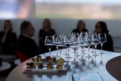 Flacons et éléments décoratifs sous cloches en verre sur une table éclairée dans un espace moderne et tamisé.