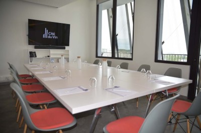 Flacons et éléments décoratifs sous cloches en verre sur une table éclairée dans un espace moderne et tamisé.