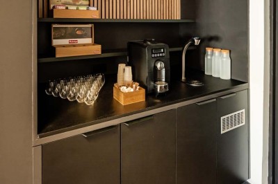 Flacons et éléments décoratifs sous cloches en verre sur une table éclairée dans un espace moderne et tamisé.