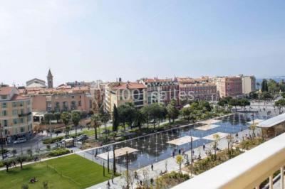 Miniature Location salle Nice (Alpes-Maritimes) - Aston La Scala Nice #5 Tables dressées avec chandelles et fleurs sur une terrasse offrant une vue nocturne sur des bâtiments éclairés.