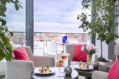 Miniature Location salle Nice (Alpes-Maritimes) - Aston La Scala Nice #17 Tables dressées avec chandelles et fleurs sur une terrasse offrant une vue nocturne sur des bâtiments éclairés.