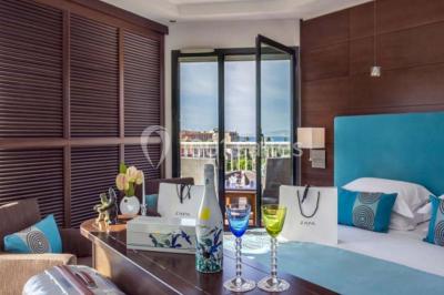 Miniature Location salle Nice (Alpes-Maritimes) - Aston La Scala Nice #14 Tables dressées avec chandelles et fleurs sur une terrasse offrant une vue nocturne sur des bâtiments éclairés.