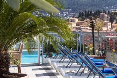 Miniature Location salle Nice (Alpes-Maritimes) - Aston La Scala Nice #12 Tables dressées avec chandelles et fleurs sur une terrasse offrant une vue nocturne sur des bâtiments éclairés.