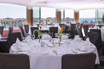 Miniature Location salle Nice (Alpes-Maritimes) - Aston La Scala Nice #15 Tables dressées avec chandelles et fleurs sur une terrasse offrant une vue nocturne sur des bâtiments éclairés.