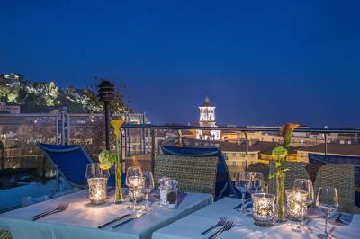 Miniature Location salle Nice (Alpes-Maritimes) - Aston La Scala Nice #24 Tables dressées avec chandelles et fleurs sur une terrasse offrant une vue nocturne sur des bâtiments éclairés.