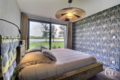 Chambre mansardée avec deux lits simples, murs en pierre apparente, lumière naturelle et décoration chaleureuse.