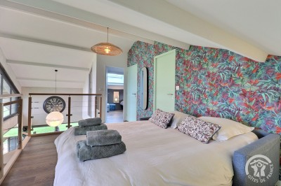 Chambre mansardée avec deux lits simples, murs en pierre apparente, lumière naturelle et décoration chaleureuse.