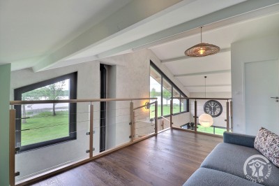 Chambre mansardée avec deux lits simples, murs en pierre apparente, lumière naturelle et décoration chaleureuse.