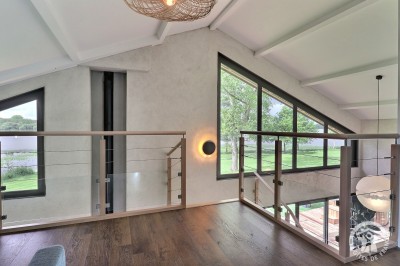 Chambre mansardée avec deux lits simples, murs en pierre apparente, lumière naturelle et décoration chaleureuse.