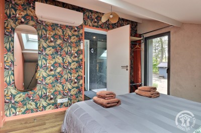 Chambre mansardée avec deux lits simples, murs en pierre apparente, lumière naturelle et décoration chaleureuse.