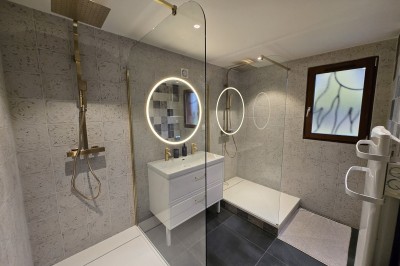 Chambre mansardée avec deux lits simples, murs en pierre apparente, lumière naturelle et décoration chaleureuse.