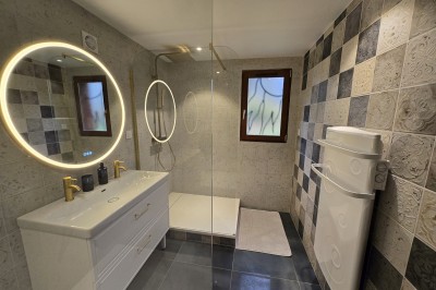 Chambre mansardée avec deux lits simples, murs en pierre apparente, lumière naturelle et décoration chaleureuse.