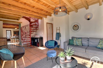 Chambre mansardée avec deux lits simples, murs en pierre apparente, lumière naturelle et décoration chaleureuse.
