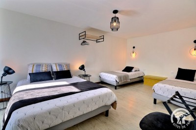 Chambre mansardée avec deux lits simples, murs en pierre apparente, lumière naturelle et décoration chaleureuse.