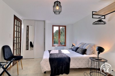 Chambre mansardée avec deux lits simples, murs en pierre apparente, lumière naturelle et décoration chaleureuse.
