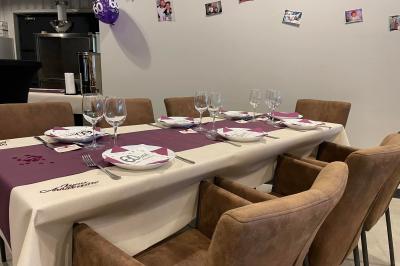 Salle décorée pour un anniversaire avec ballons noirs et dorés, tables dressées et une scène en fond.