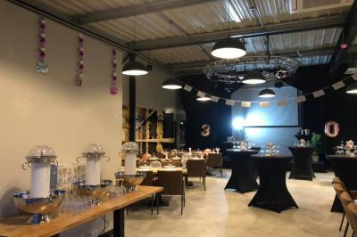 Salle décorée pour un anniversaire avec ballons noirs et dorés, tables dressées et une scène en fond.