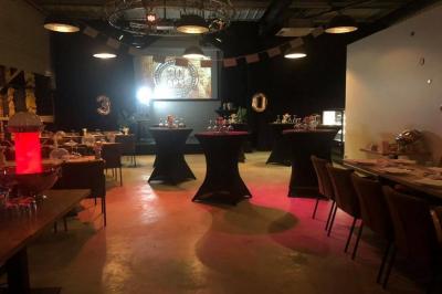 Salle décorée pour un anniversaire avec ballons noirs et dorés, tables dressées et une scène en fond.