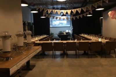 Salle décorée pour un anniversaire avec ballons noirs et dorés, tables dressées et une scène en fond.