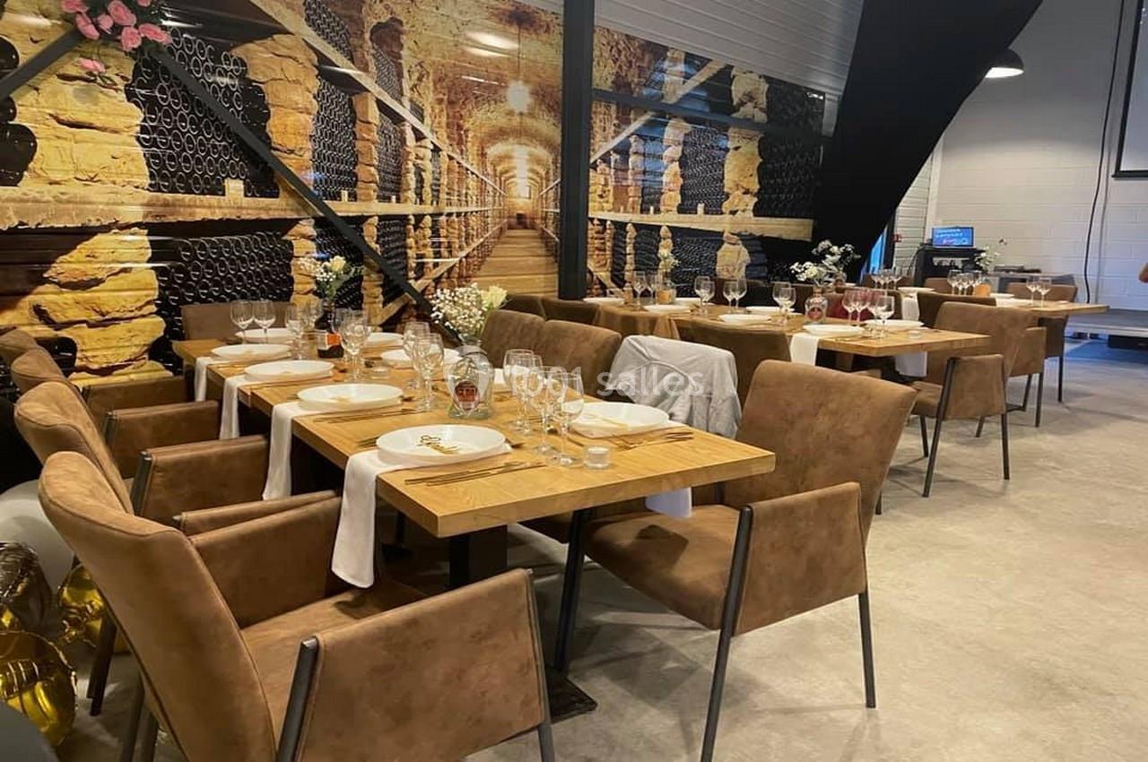 Salle de restaurant avec tables dressées, chaises en cuir marron et décoration murale représentant une cave à vin.
