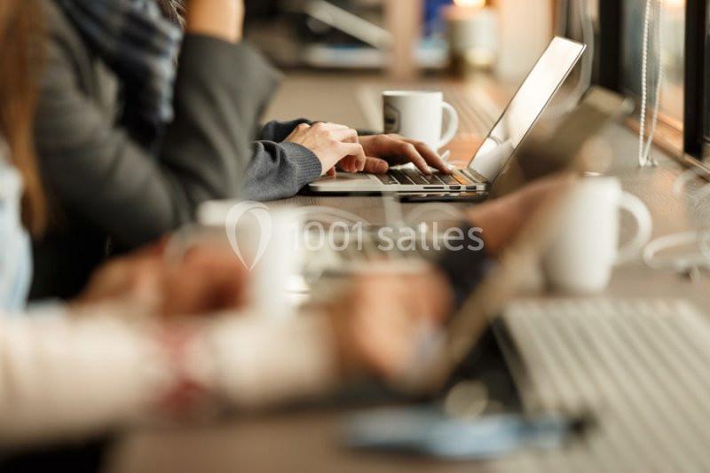 Personnes travaillant sur des ordinateurs portables dans un espace partagé avec des tasses de café sur la table.
