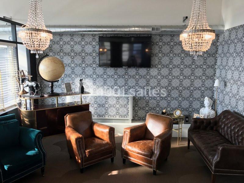 Salon élégant avec fauteuils en cuir, canapé, globe terrestre, chandeliers et mur décoré de motifs géométriques.