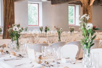 Chambre lumineuse avec poutres apparentes, lit double, commode en bois et fenêtres donnant sur l'extérieur.