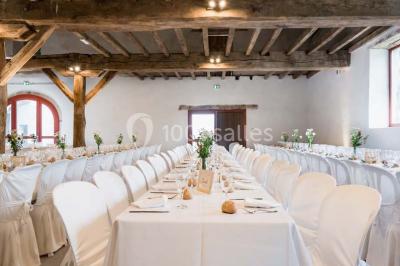 Chambre lumineuse avec poutres apparentes, lit double, commode en bois et fenêtres donnant sur l'extérieur.
