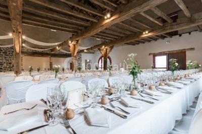 Chambre lumineuse avec poutres apparentes, lit double, commode en bois et fenêtres donnant sur l'extérieur.