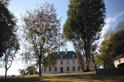 Chambre lumineuse avec poutres apparentes, lit double, commode en bois et fenêtres donnant sur l'extérieur.