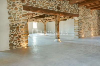 Chambre lumineuse avec poutres apparentes, lit double, commode en bois et fenêtres donnant sur l'extérieur.
