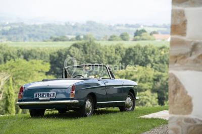 Chambre lumineuse avec poutres apparentes, lit double, commode en bois et fenêtres donnant sur l'extérieur.