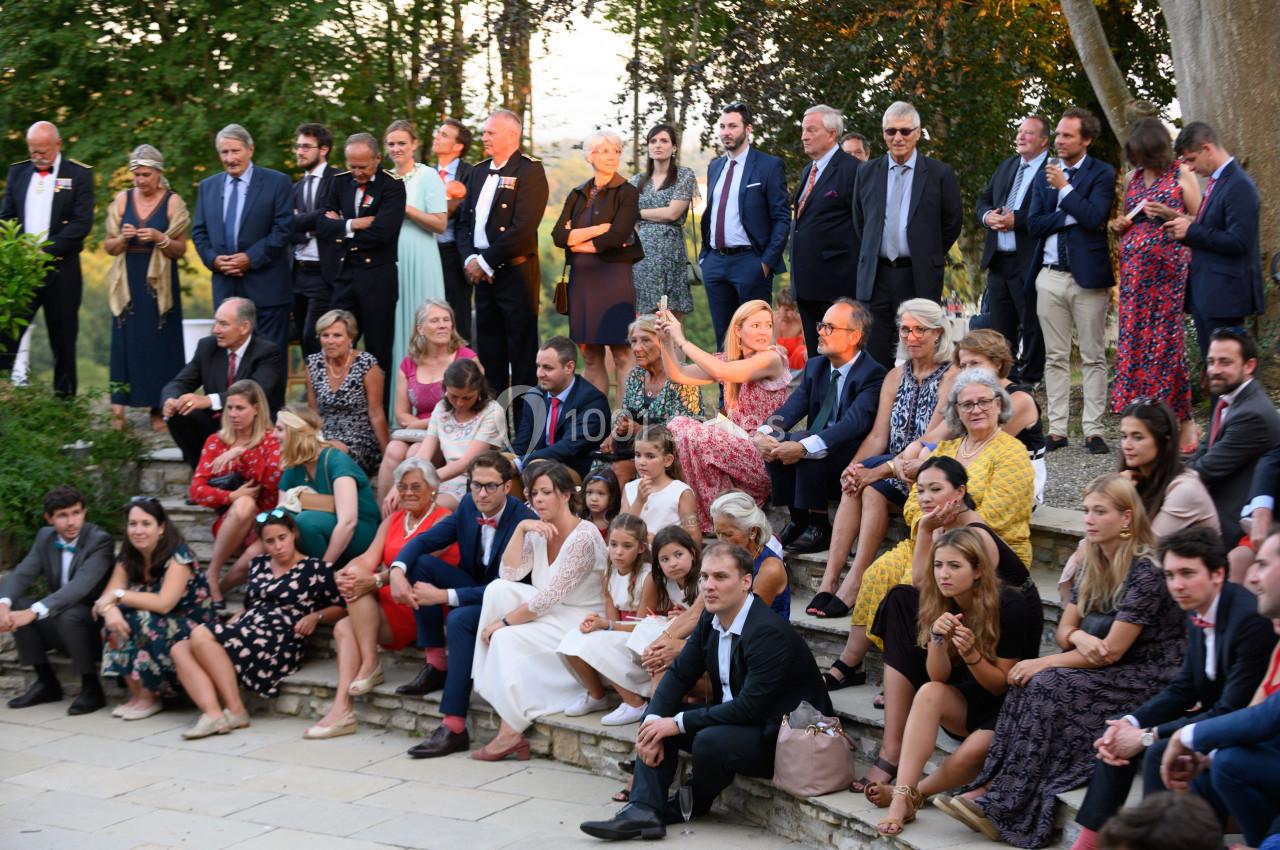Un groupe de personnes assises et debout lors d'un événement en plein air, entouré de végétation.