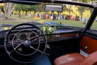 Chambre lumineuse avec poutres apparentes, lit double, commode en bois et fenêtres donnant sur l'extérieur.