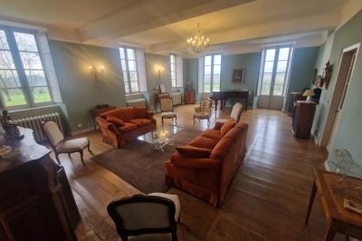 Chambre lumineuse avec poutres apparentes, lit double, commode en bois et fenêtres donnant sur l'extérieur.