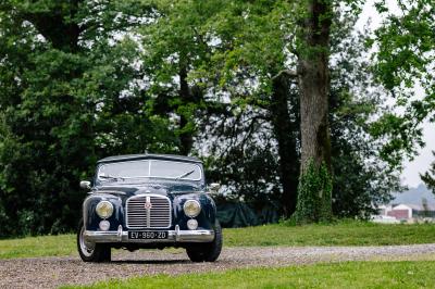 Chambre lumineuse avec poutres apparentes, lit double, commode en bois et fenêtres donnant sur l'extérieur.