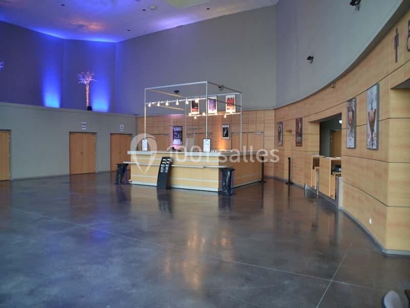 Hall d'accueil spacieux avec comptoir en bois, murs courbes, éclairage tamisé et affiches décoratives.