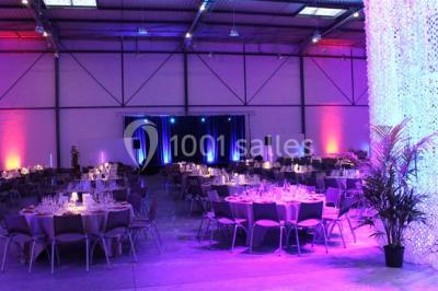 Entrée vitrée illuminée avec des plantes en pot disposées en rangées et éclairage coloré.