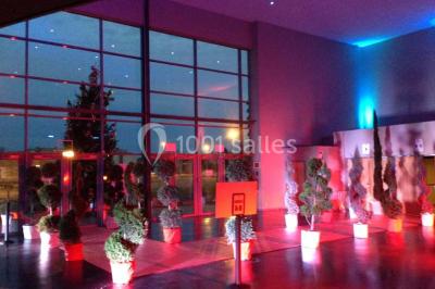 Entrée vitrée illuminée avec des plantes en pot disposées en rangées et éclairage coloré.