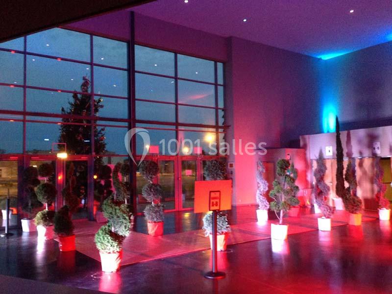 Entrée vitrée illuminée avec des plantes en pot disposées en rangées et éclairage coloré.