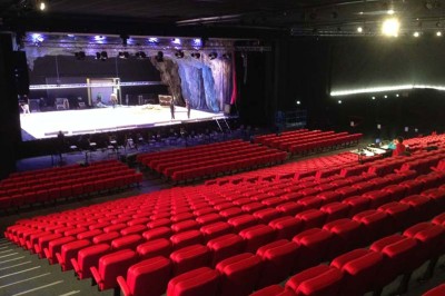 Entrée vitrée illuminée avec des plantes en pot disposées en rangées et éclairage coloré.