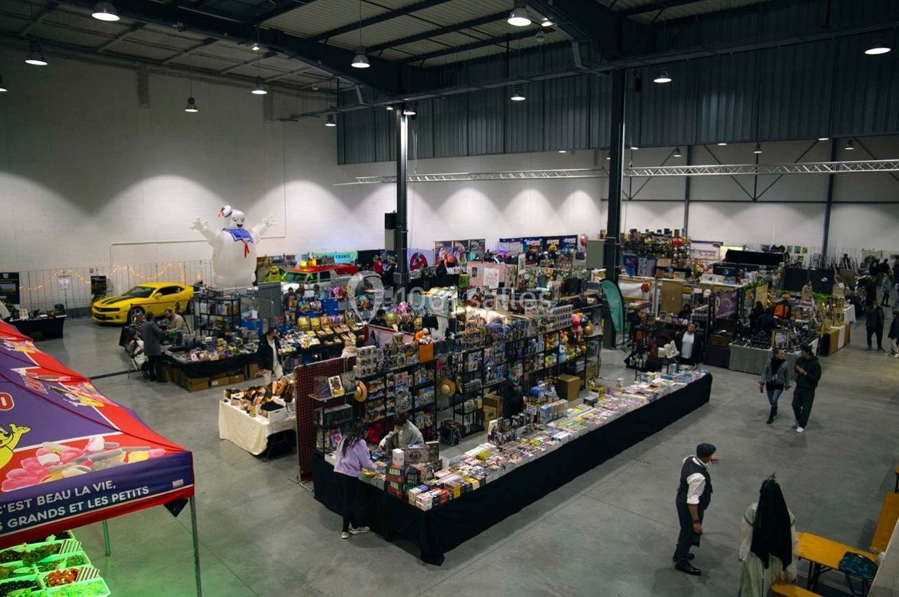 Vue d'ensemble d'un salon avec des stands de produits variés, des visiteurs et une décoration intérieure lumineuse.