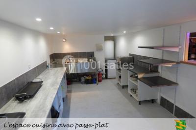 Table en bois décorée pour un repas festif, avec bougies, fleurs et vaisselle, dans une salle aux murs en pierre.