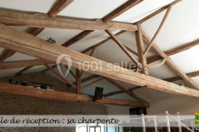 Table en bois décorée pour un repas festif, avec bougies, fleurs et vaisselle, dans une salle aux murs en pierre.