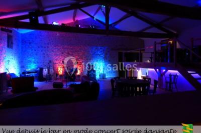 Table en bois décorée pour un repas festif, avec bougies, fleurs et vaisselle, dans une salle aux murs en pierre.
