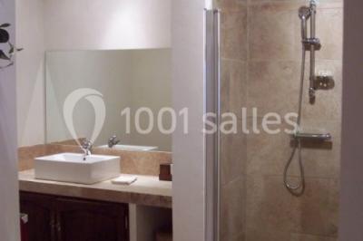 Table en bois décorée pour un repas festif, avec bougies, fleurs et vaisselle, dans une salle aux murs en pierre.